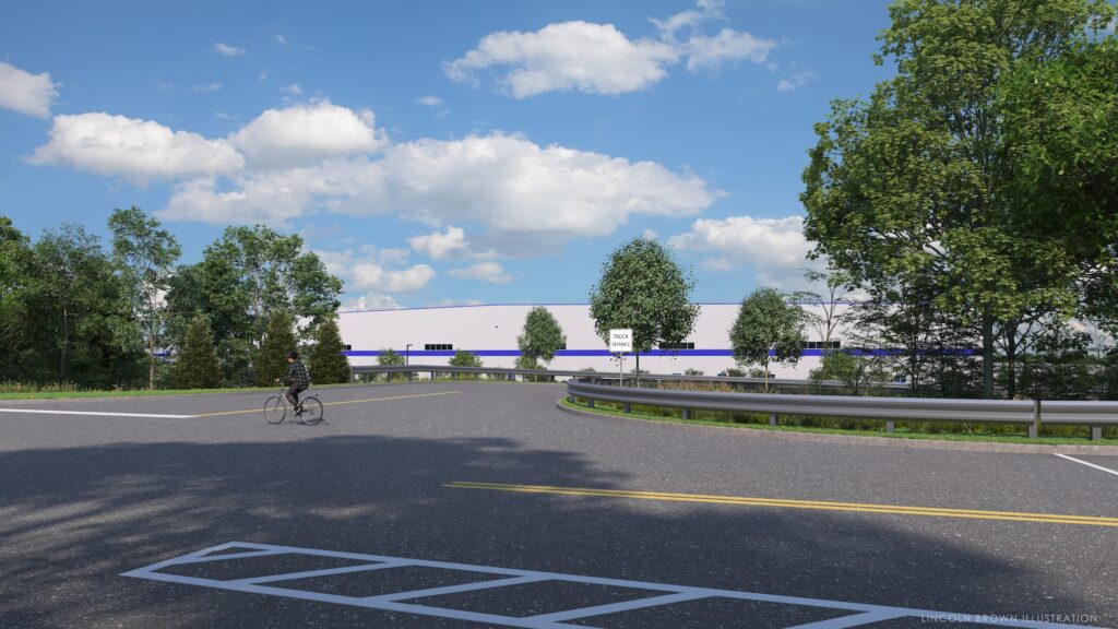 A cyclist rides along a road bordered by trees under a partly cloudy sky. In the background, a large white industrial building is visible. The scene is peaceful and captures a blend of nature and infrastructure.