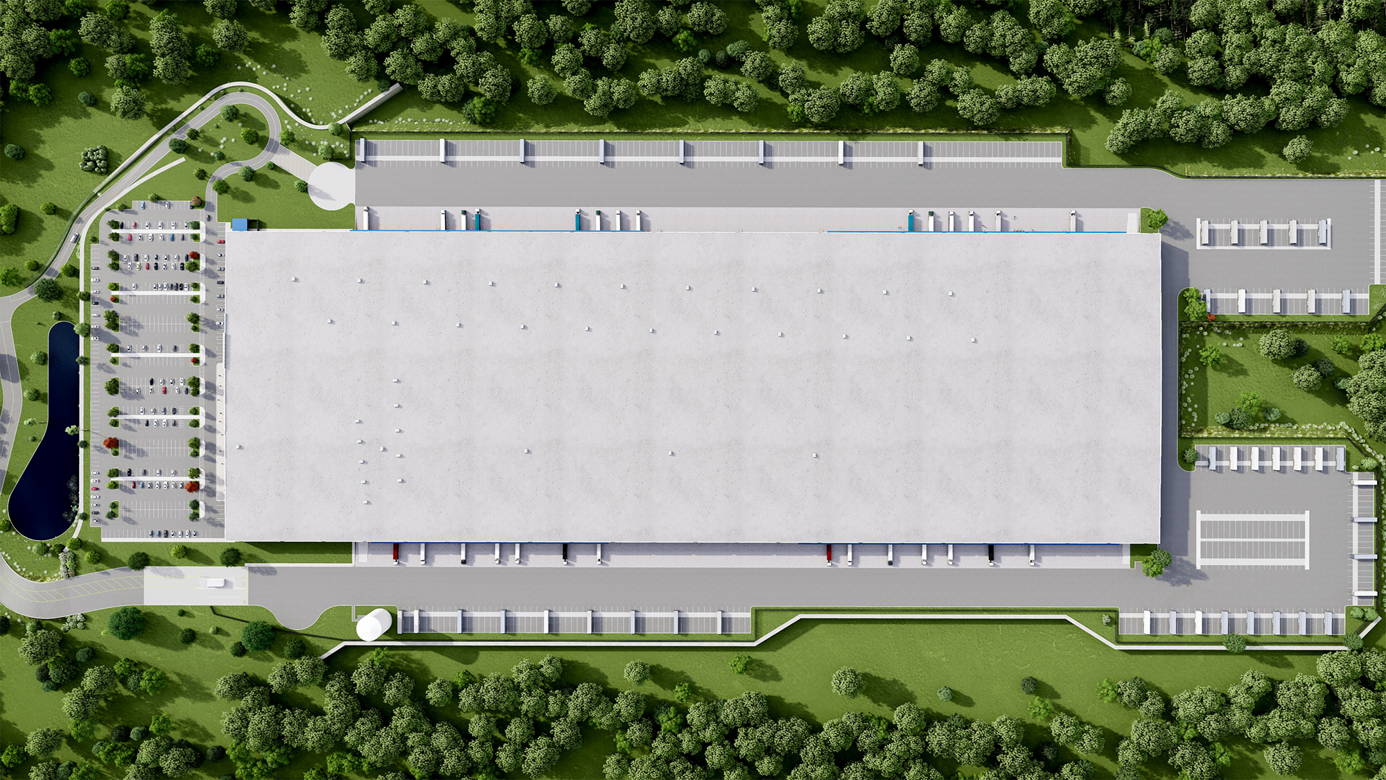 Aerial view of a large, rectangular industrial building surrounded by greenery and trees. There are parking lots on the left, driveways, and loading docks along the sides. Pathways and landscaped areas are visible around the premises.