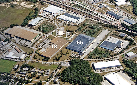 Aerial view of an industrial complex with labeled buildings numbered 18 and 66. Roads, green spaces, and surrounding buildings are visible. Note the labeled Independence Drive and Saratoga Boulevard.